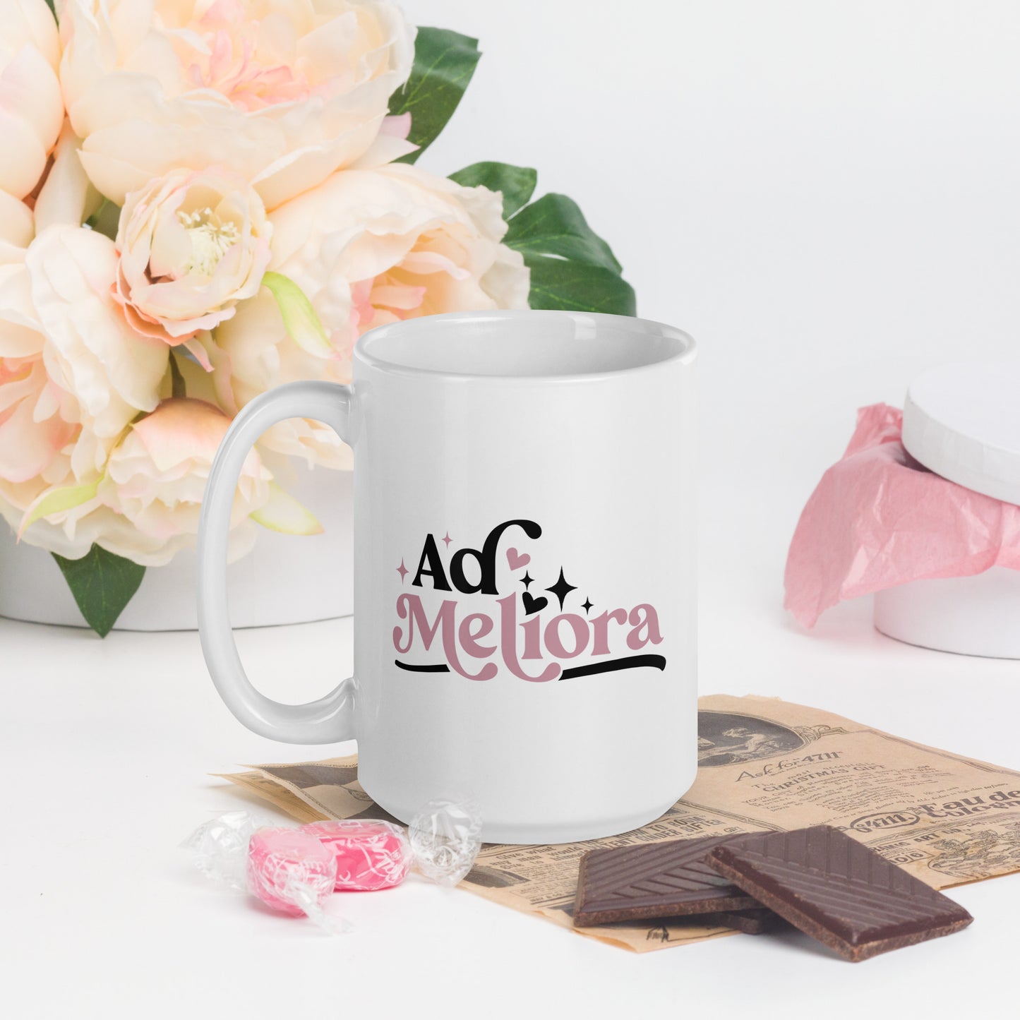 A white coffee cup with Ad Meliora written in black and pink
