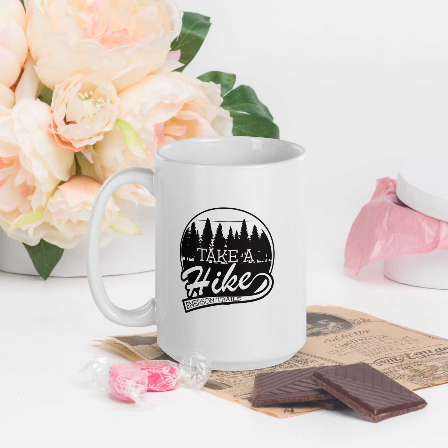 A white coffee mug with the Emerson Trails Logo. The Emerson Trails Logo shows a forest, with the words Take A Hike - Emerson Trails"