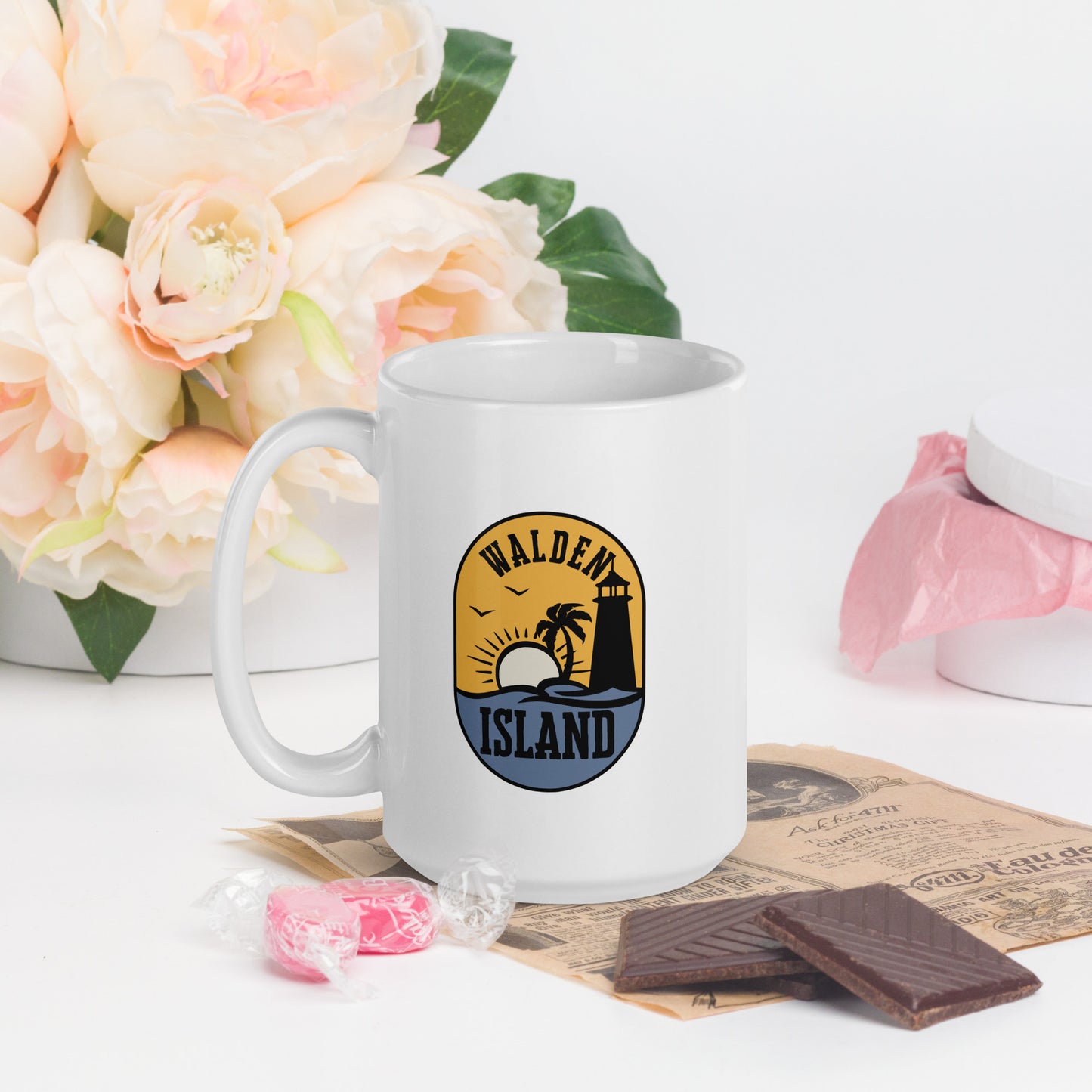 A white coffee mug with the Walden Island Logo. The Walden Island Logo show a stylized sun setting over an island in the sea, with a lighthouse and palm tree on the island.