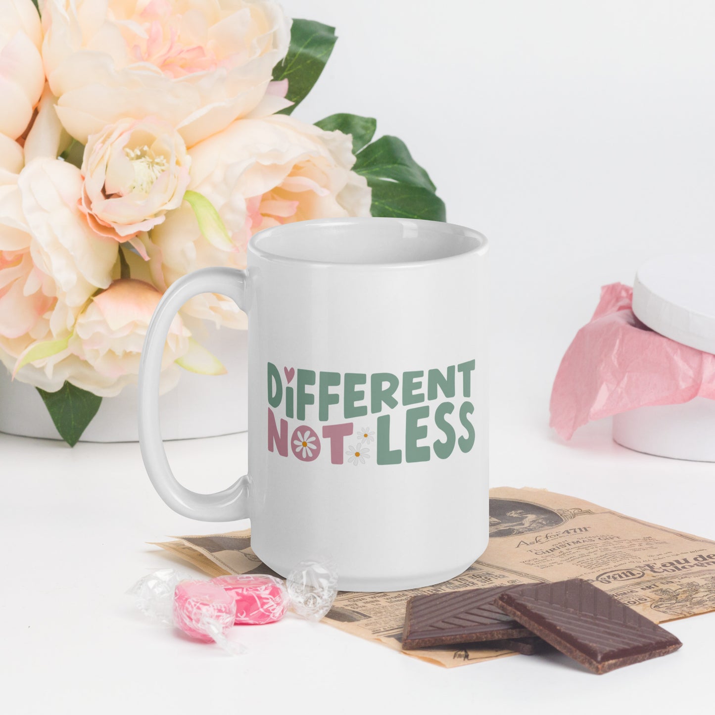 Different Not Less written in green and pink, with a pink swirl in the O of Not, on a white coffee mug
