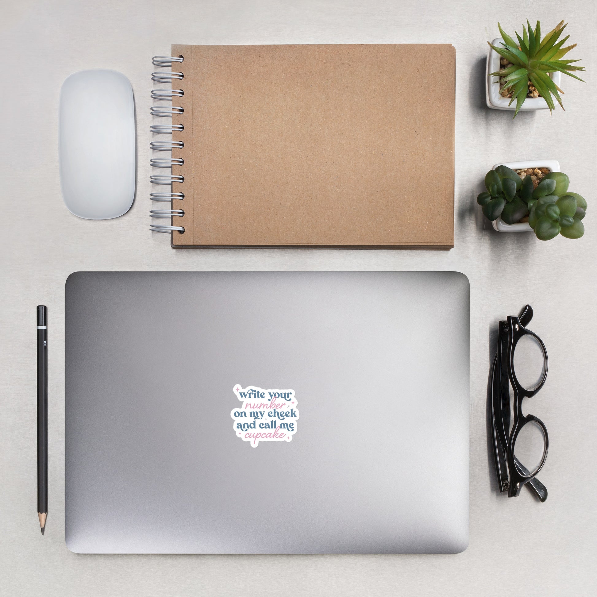 A sticker with blue and pink text, a combination of print and cursive that reads "Write Your Number on my cheek and call me cupcake". The sticker is 4 x 4 inches