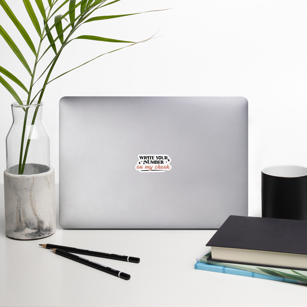 a sticker that reads "Write Your Number On My Cheek" with black lettering for "write your number" and "on my cheek" in pink cursive. The sticker is 3 x 3 inches