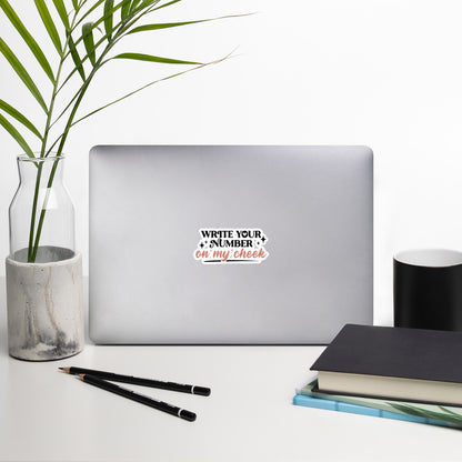 a sticker that reads "Write Your Number On My Cheek" with black lettering for "write your number" and "on my cheek" in pink cursive. The sticker is 4 x 4 inches