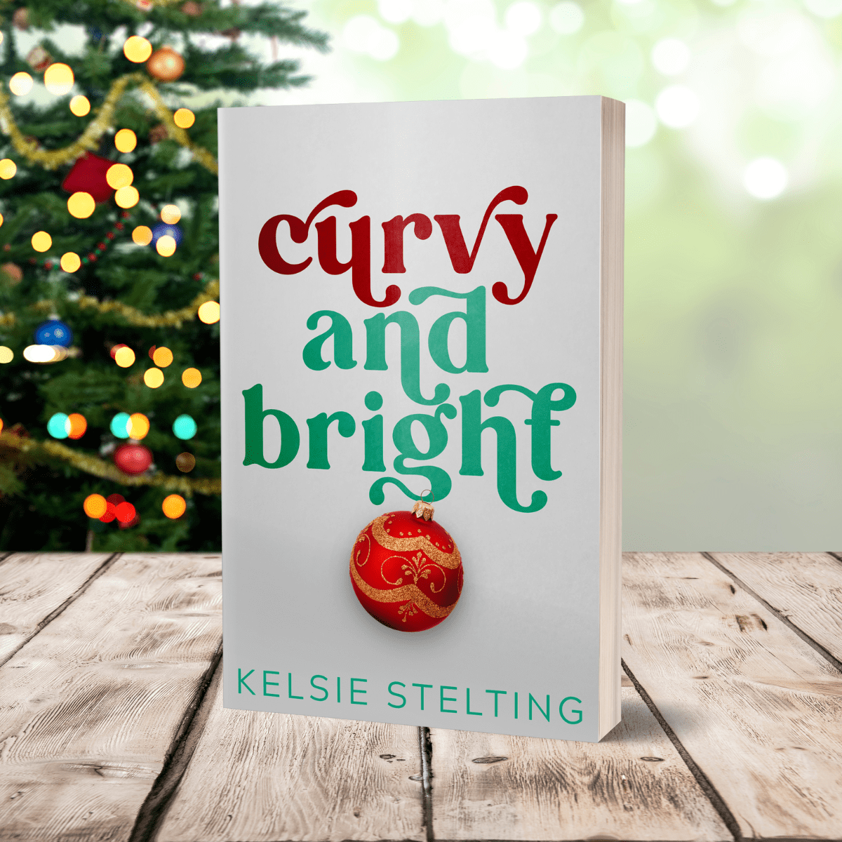 An paperback sits on a table, with christmas lights behind it. The book is titled Curvy and Bright by Kelsie Stelting and features a christmas ornament on the front