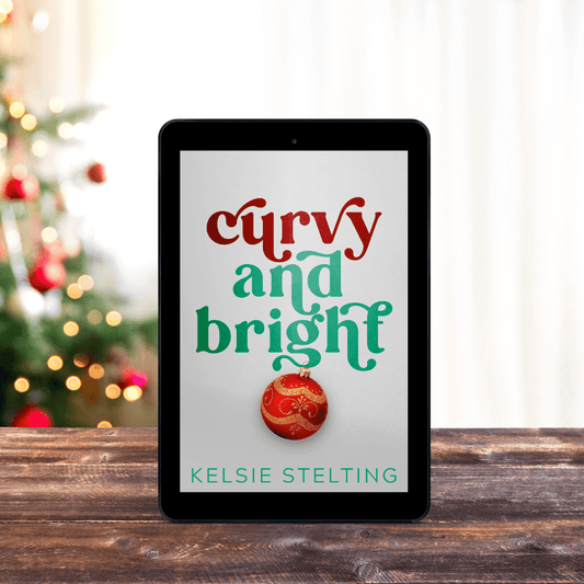 An ebook cover sits on a table, with christmas lights behind it. The book is titled Curvy and Bright by Kelsie Stelting and features a christmas ornament on the front