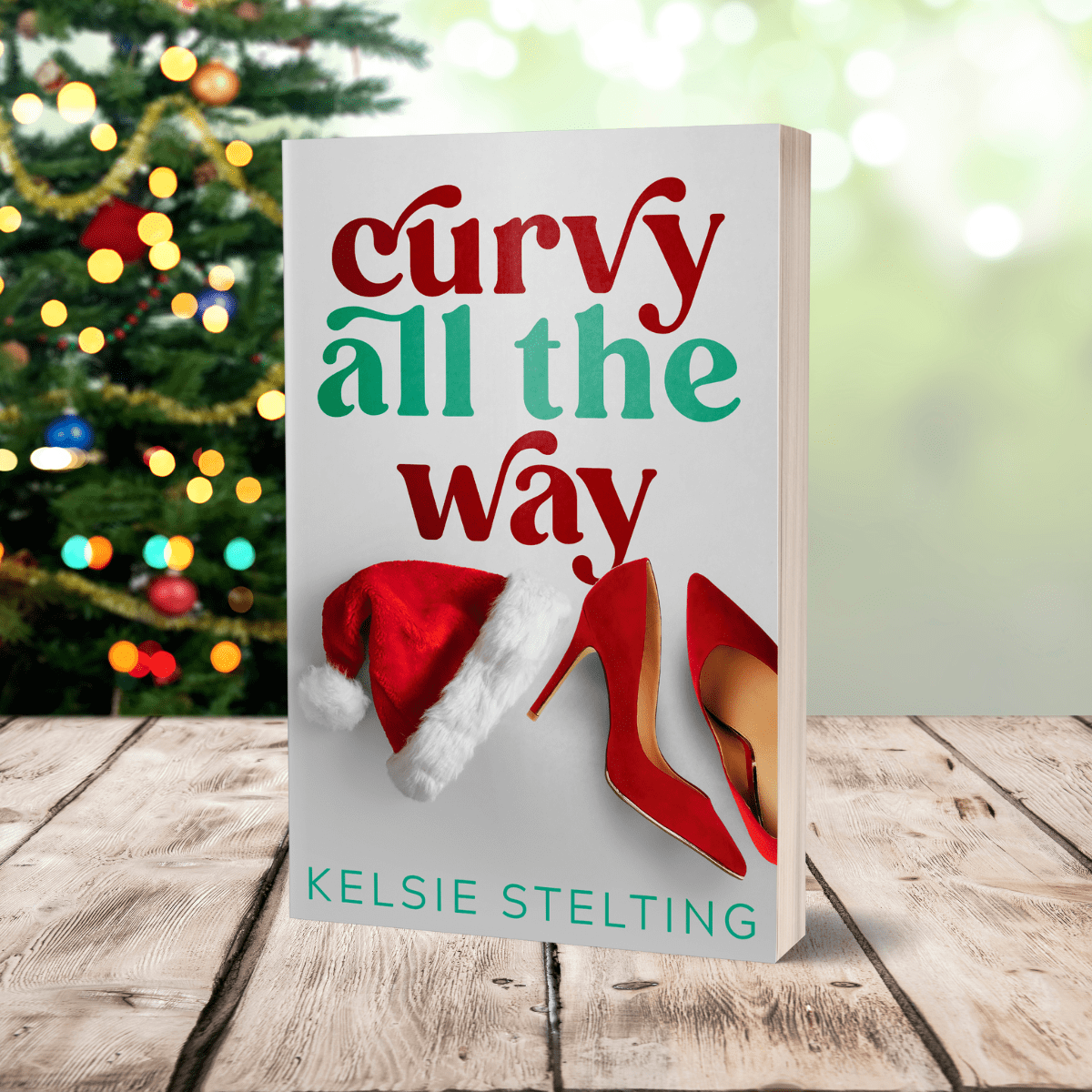 An paperback cover sits on a table, with christmas lights behind it. The book is titled Curvy All the Way by Kelsie Stelting and features a santa hat and red heels on the cover