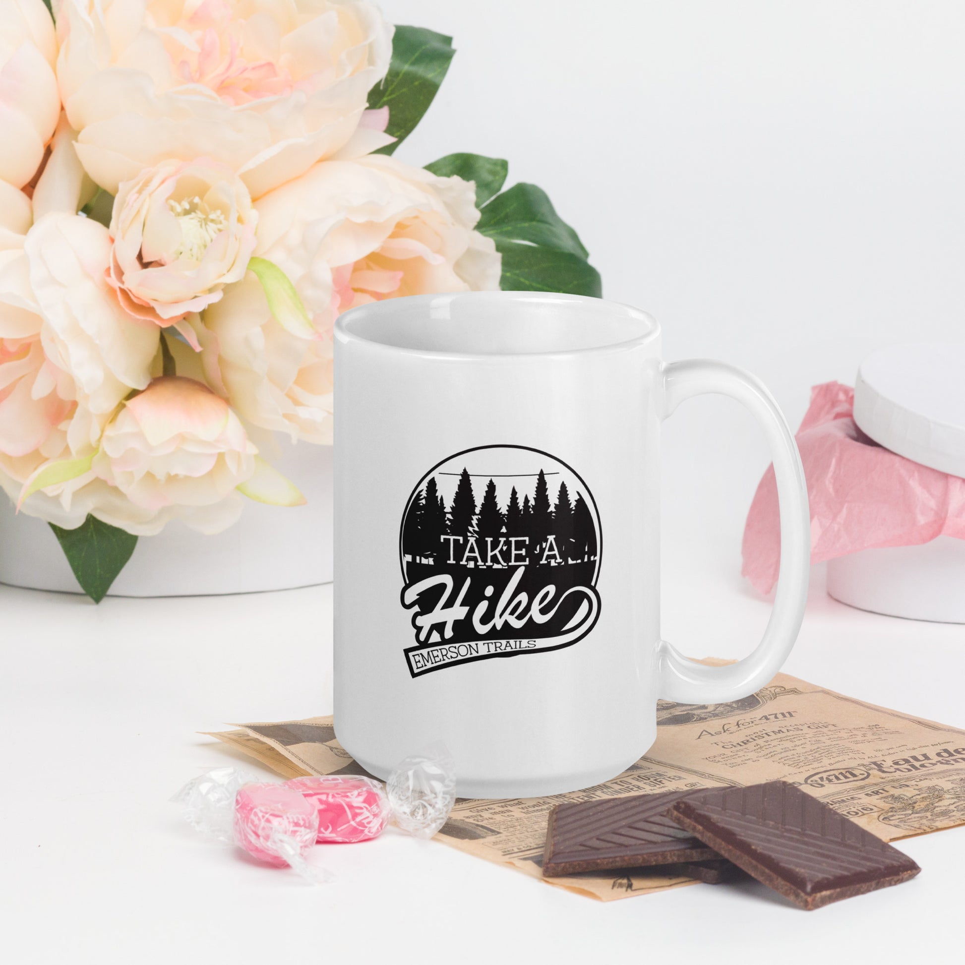 A white coffee mug with the Emerson Trails Logo. The Emerson Trails Logo shows a forest, with the words Take A Hike - Emerson Trails"