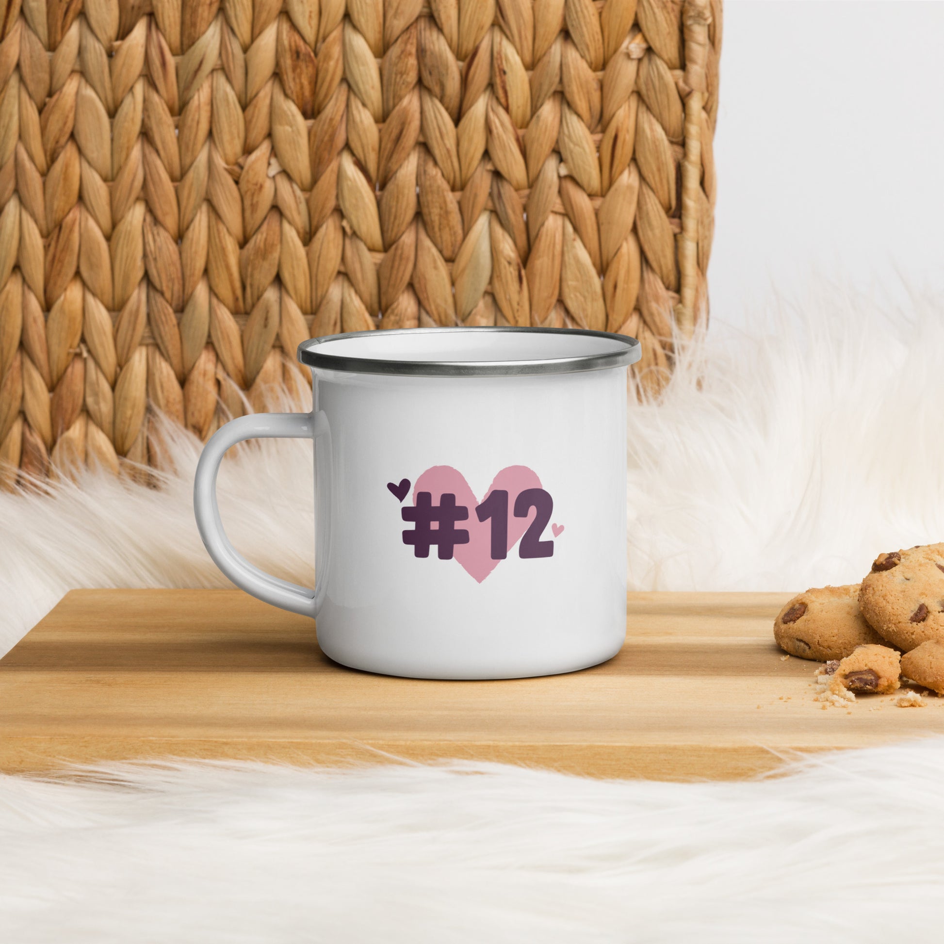a white enamel mug with the I Heart #12 Logo. The Number 12 Logo is a large pink heart with #12 in black written over the heart. 