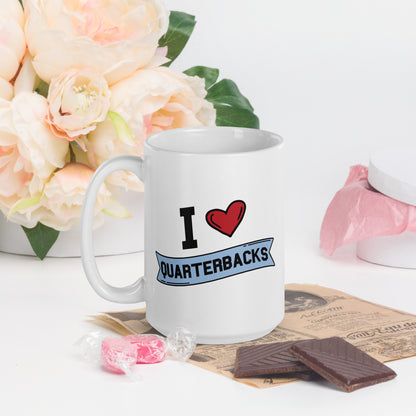 A white mug that reads I Heart Quarterbacks, with a large heart logo. Quarterbacks is in a blue banner 