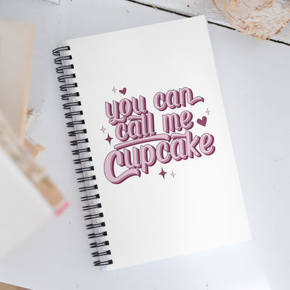 a spiral notebook that reads You Can Call Me Cupcake on the cover in big pink bubble letters. 