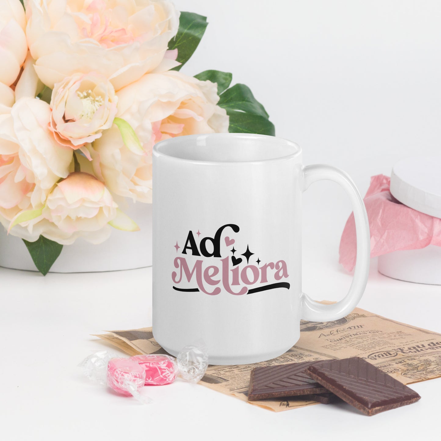 A white coffee cup with Ad Meliora written in black and pink
