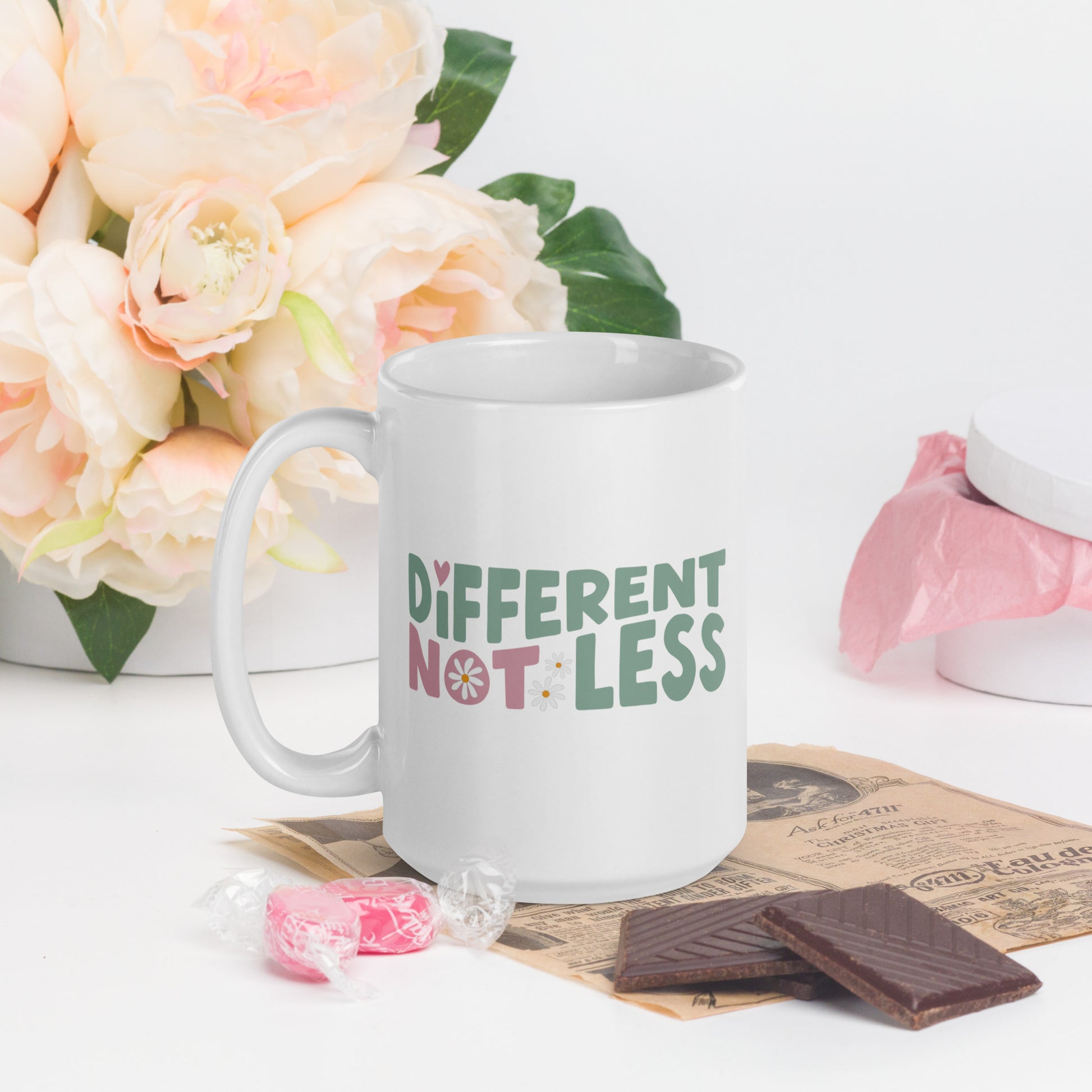 Different Not Less written in green and pink, with a pink swirl in the O of Not, on a white coffee mug