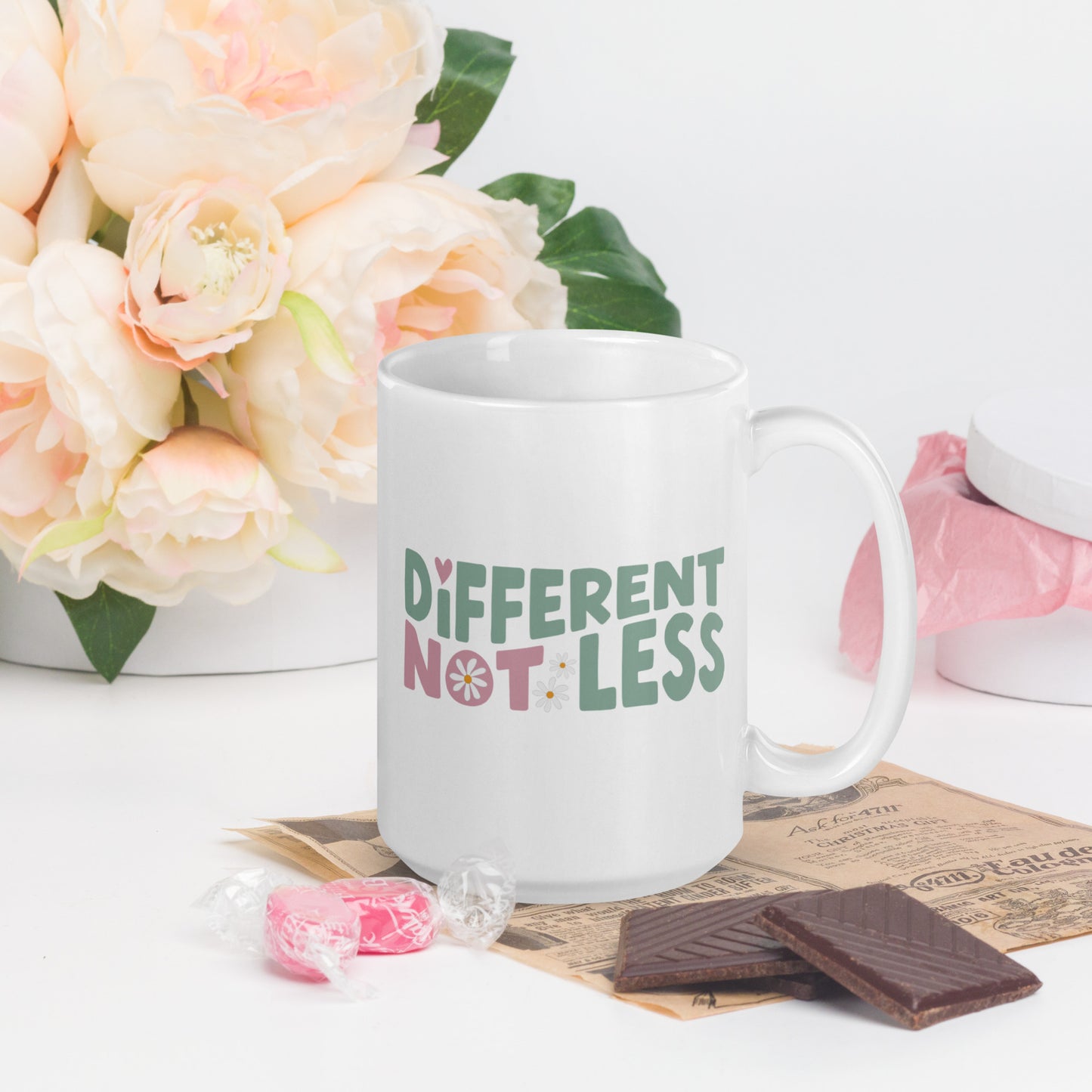 Different Not Less written in green and pink, with a pink swirl in the O of Not, on a white coffee mug