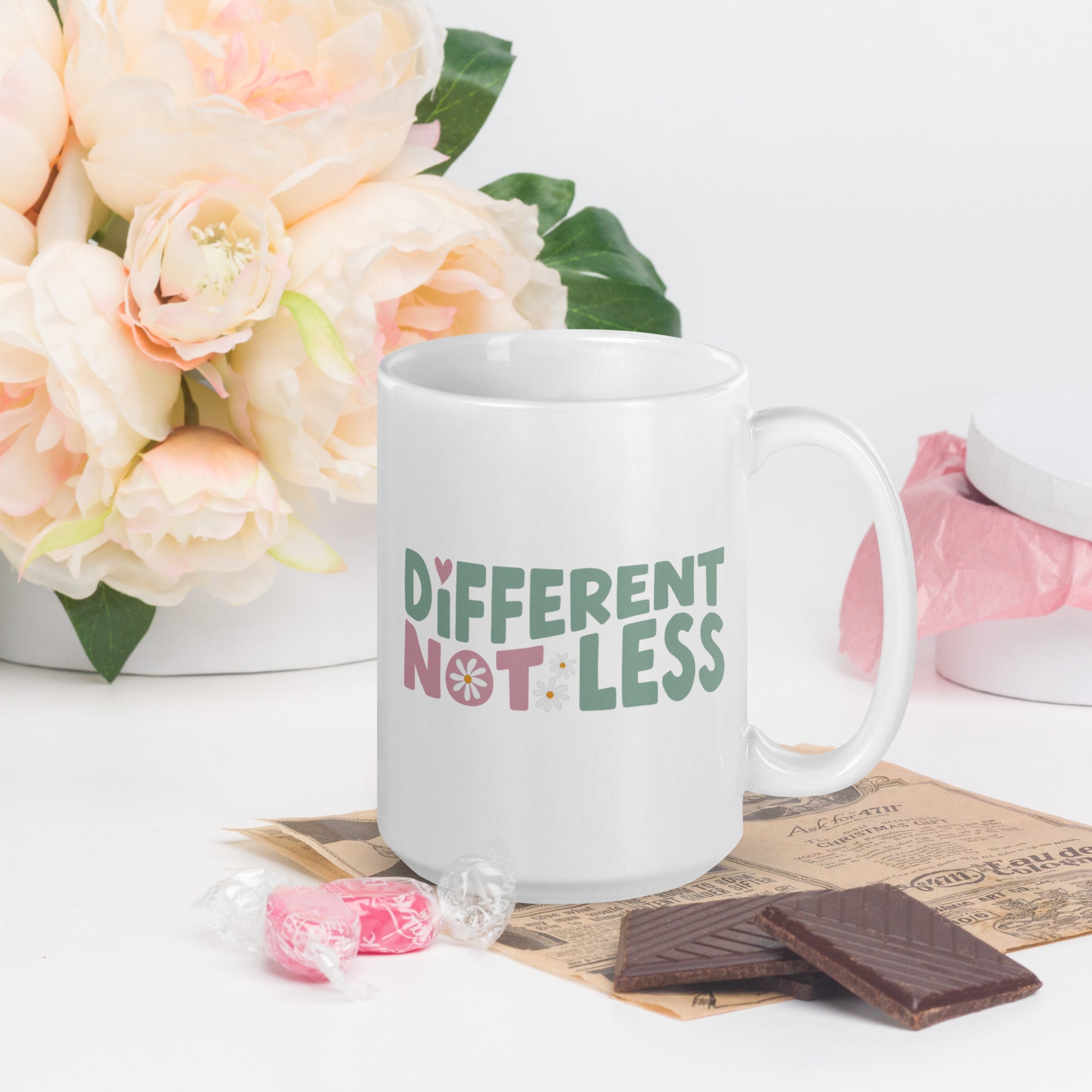 Different Not Less written in green and pink, with a pink swirl in the O of Not, on a white coffee mug