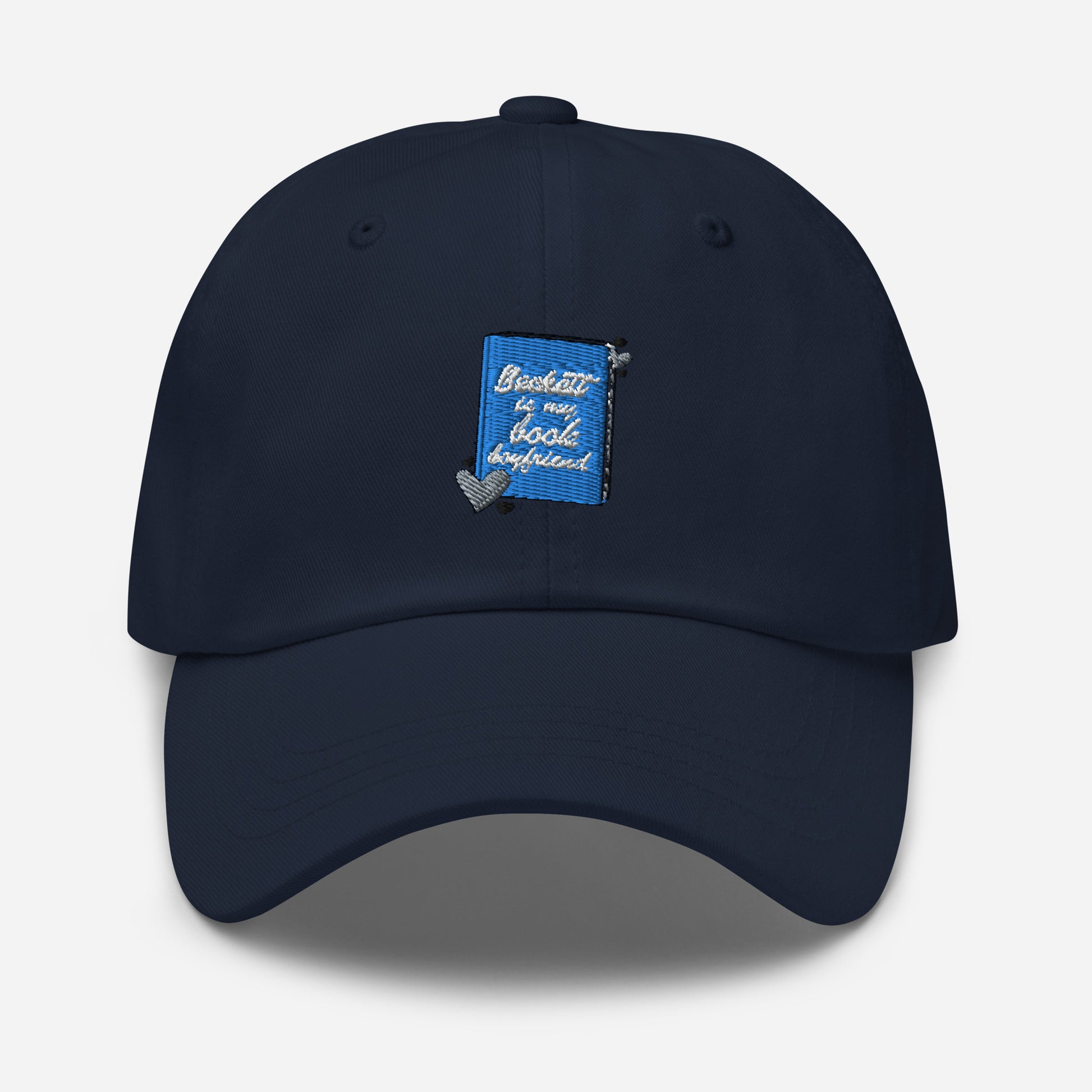 a navy cap with the Beckett logo. The Beckett Logo is a blue book with the words Beckett is my book Boyfriend in cursive, with hearts around the book. 
