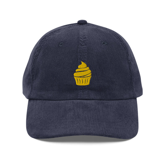 A navy blue corduroy cap with a cupcake logo