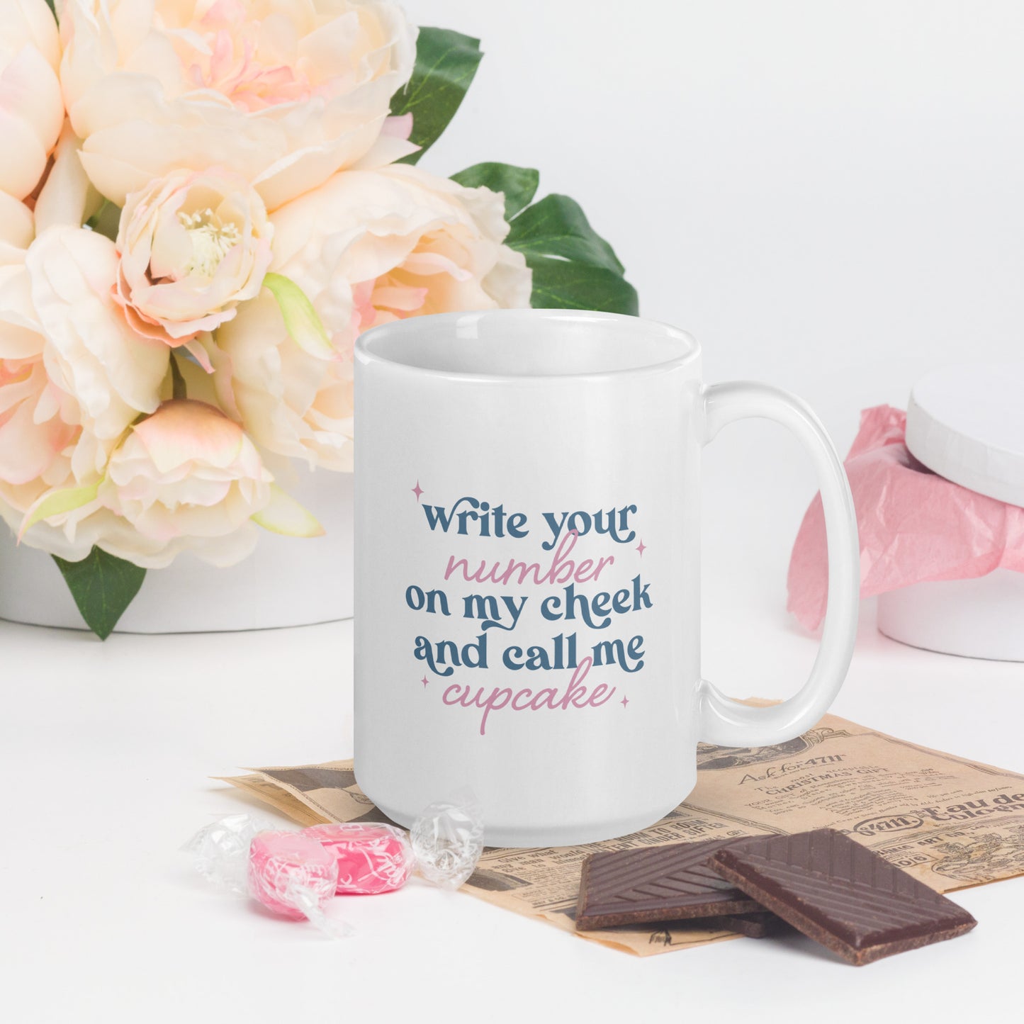 A white mug that reads "Write your number on my cheek and call me cupcake" in pink and blue lettering