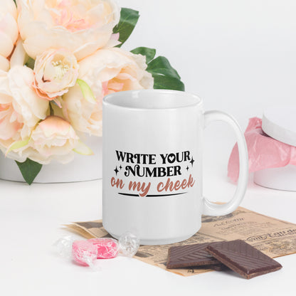 A white coffee mug that reads Write Your number in my cheek in black print and golden cursive
