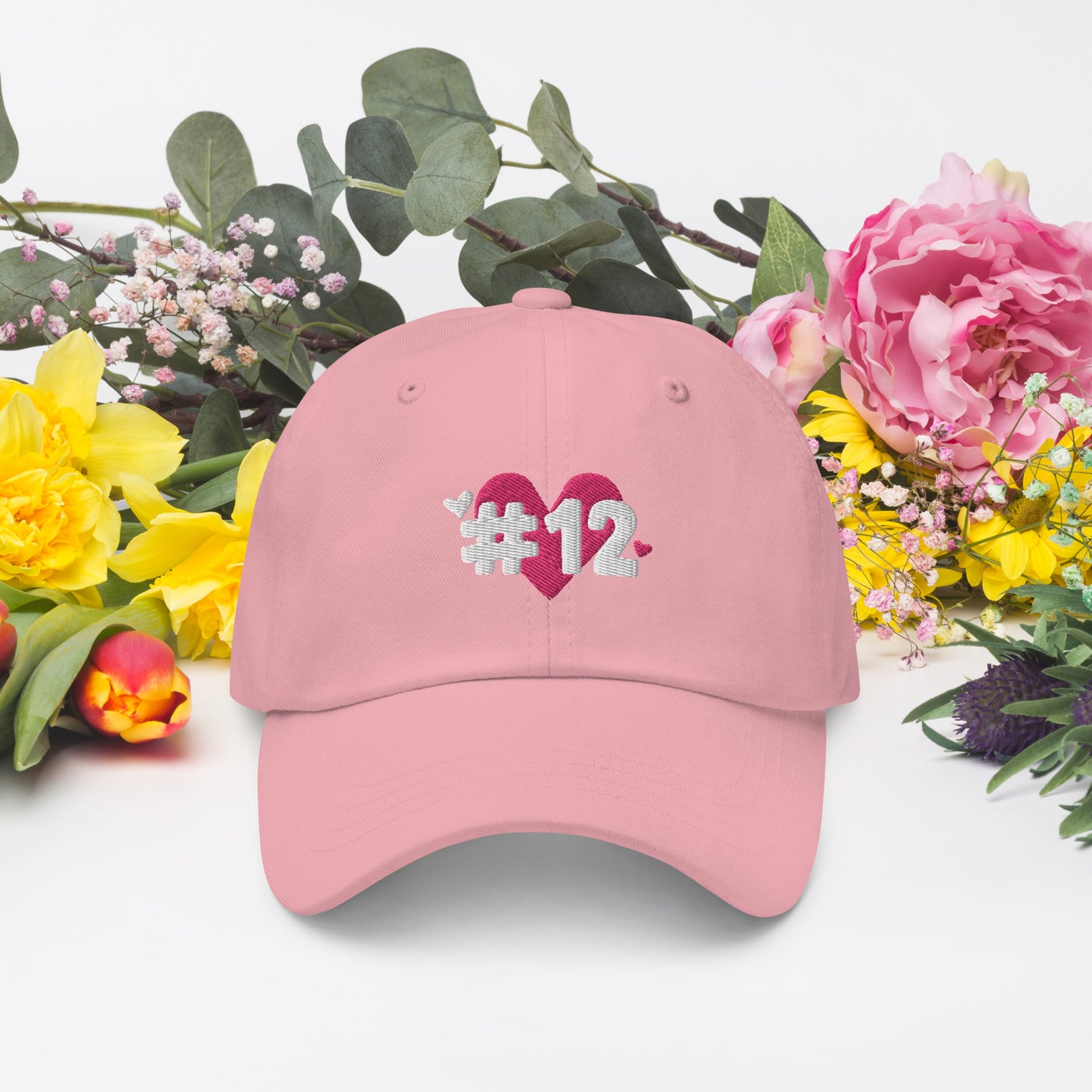 a pink cap with the I Heart #12 Logo. The Number 12 Logo is a large pink heart with #12 in black written over the heart.
