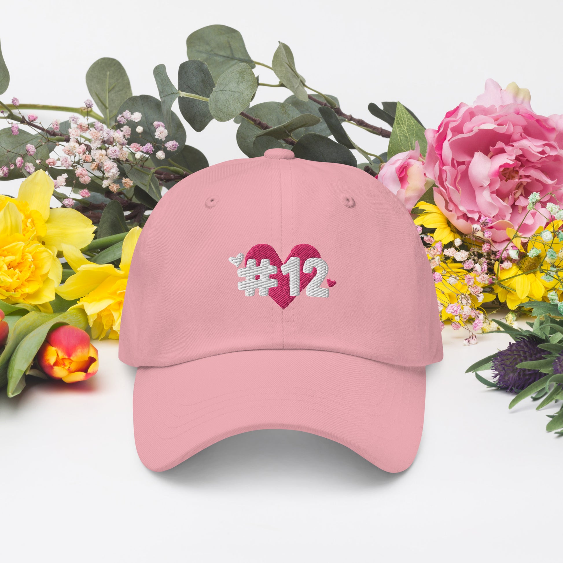 a pink cap with the I Heart #12 Logo. The Number 12 Logo is a large pink heart with #12 in black written over the heart.