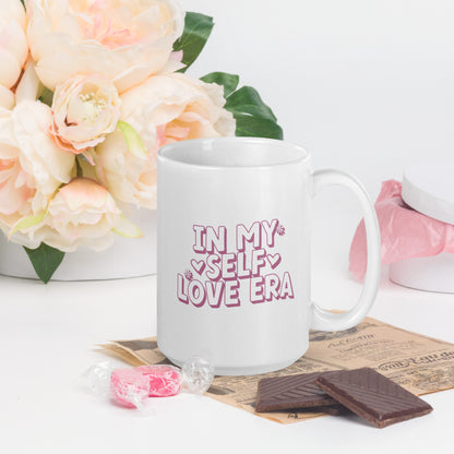 A white mug that reads "In my Self Love Era" in pink bubble lettering, with heart designs