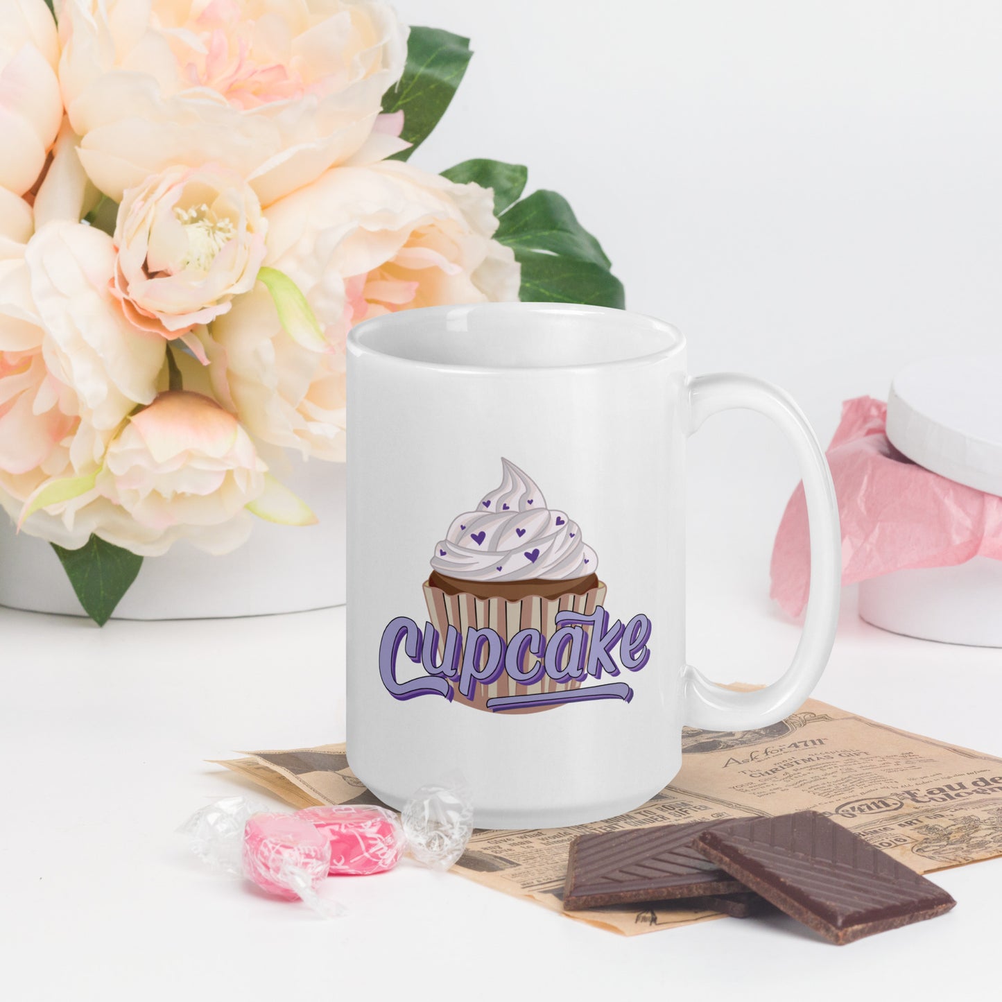 a glossy white mug with a cupcake logo. The cupcake logo is a large cupcake covered in sprinkles, with cupcake written over it in pink block letters