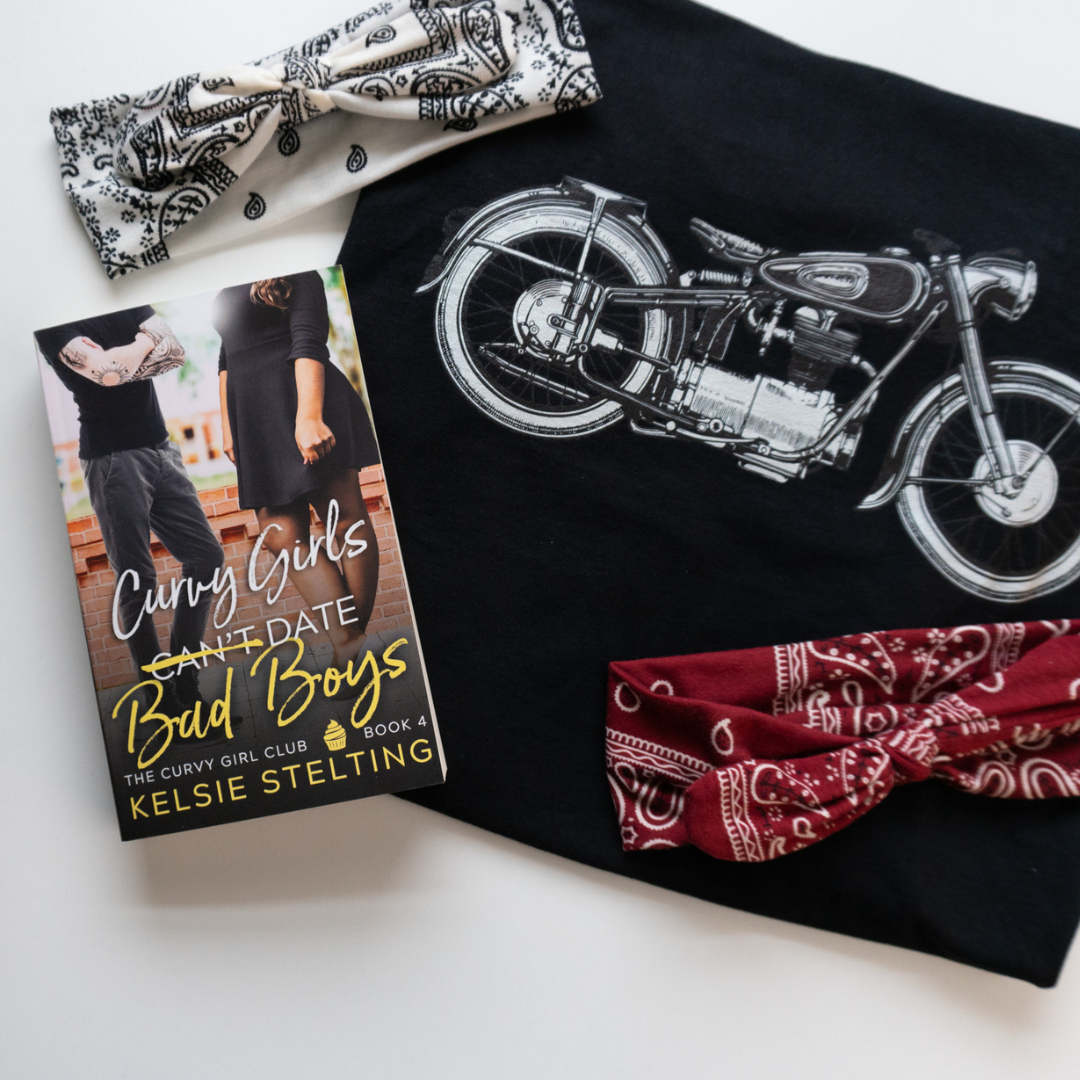 A paperback book surrounded by bandanas and a motorcycle shows a book cover.  The book's title is Curvy Girls Can't Date Bad Boys, The Curvy Girl Club Book 4, by author Kelsie Stelting